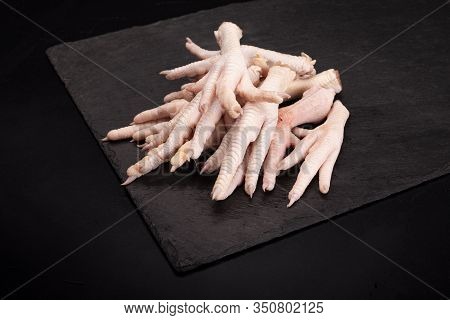 Raw Chicken Feet On A Dark Stony Background.