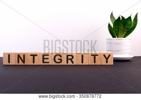 Integrity Word Concept Written On Wooden Blocks, Cubes On A Dark Table With A Flower And A Light Bac