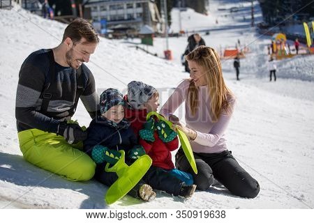 Parents With Children Playing On Snow. Family Winter Vacation