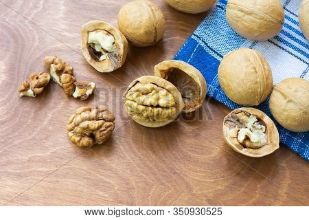 Whole Walnuts And Walnut Kernel Halves Without Shell On A Dark Wooden Table And Checkered Towel, Clo