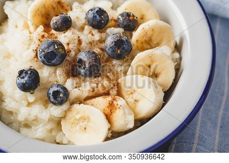 Close Uo Of Milk Rice Porridge With Blueberry, Banana, Honey And Cinnamon, Creamy Rice Pudding Or Fr
