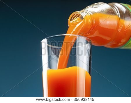 Carrot Juice Is Poured From A Bottle Into A Glass