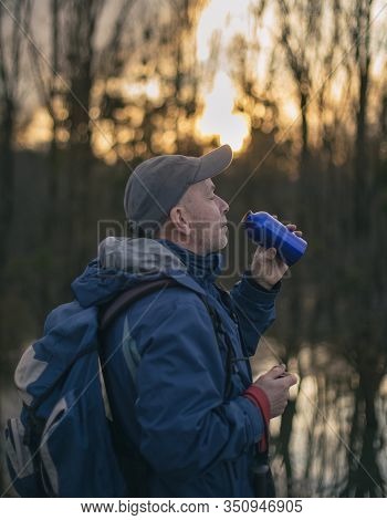 Mature Hiker With Backpack Drinking Water From Bottle In Forest