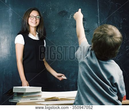 Little Cute Boy In Glasses With Young Real Teacher, Classroom Studying At Blackboard School Kido