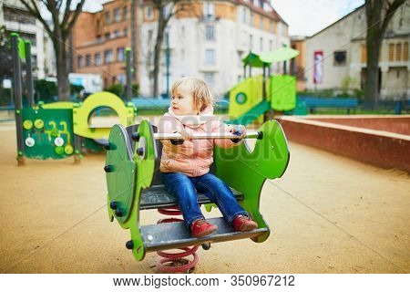Adorable Toddler Girl Having Fun On Spring Rider On Playground. Outdoor Activities For Kids