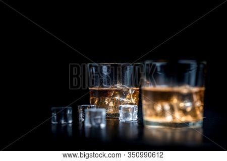 Whisky, Whiskey, Bourbon Or Cognac With Ice Cudes On Black Stone Table