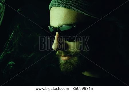 Portrait Of A Bearded, White Hipster Smoker On A Dark Background. Studio Stock Photo Concept Of Smok