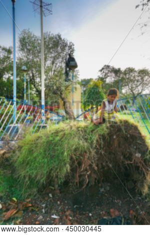 Blurred Image Of Kolkata, West Bengal, India. Girl Children Are Playing On A Tree, Uprooted By Super