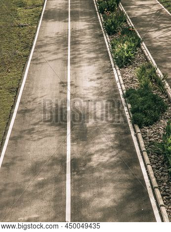 Top View Of Empty Road Texture With Median Strip In The Middle Surrounded Green Grass. Selective Foc