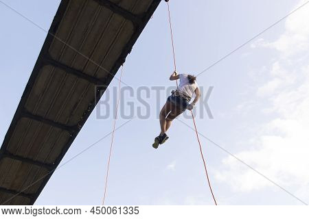 Woman Practicing Rappel On A Pedestrian Walkway.