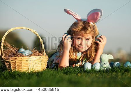 Child Boy With Easter Eggs In Basket Outdoor. Kid Laying On Grass In Park On Sky Background With Cop