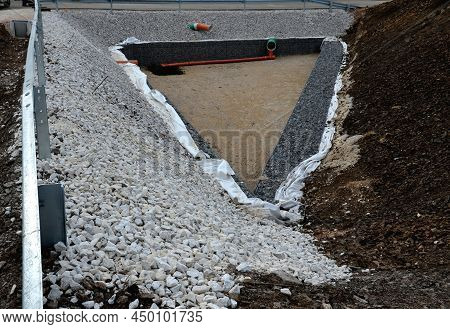 Triangle-shaped Drainage Pond With Stone Wall Paneling And Gabion Walls. The Water Slows Down During