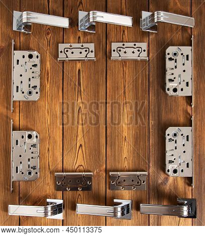 Set Of Door Hardware On A Wooden Background. Magnetic Latch, Door Hinges And Door Handles. Copy Spac