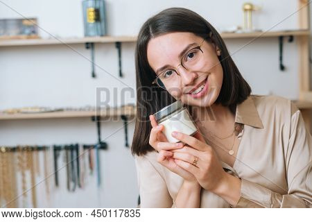 Close-up Portrait Of Attractive Young Woman In Glasses Holding Little Transparent Glass Jar With Han