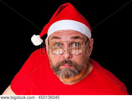 Surprised Santa Claus Looks At Us. Unusual Santa Claus Isolated On Black Background. Middle-aged Man