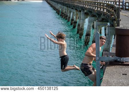 Tolaga Bay New Zealand - February 5 2022; Local Boys Jumping Of And Climbing Up Tolaga Bay Wharf