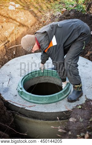 A Worker Installs A Manhole On A Septic Tank. Conducting Communications In A Residential Building.