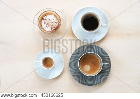 Group Of Cups With Various Coffee, Espresso, Cappuccino, Lungo Black And With Crema On A Light Woode