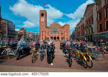 Amsterdam, Netherlands - May 7, 2017: Beursplein with parked bicycles motorcycles and Beurs van Berlage building former commodity exchange building now venue for concerts, exhibitions and conferences