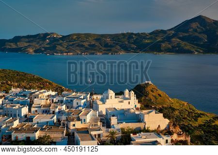 View of Plaka village on Milos island with traditional greek white houses with Greek Orthodox christian churck on sunset. Plaka town, Milos island, Greece