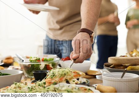 Man Taking Slice Of Pizza From Buffet Indoors, Closeup. Brunch Table Setting