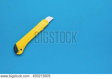 Stylish Yellow Stationery Knife On A Bright Blue Background. Minimalistic Concept.