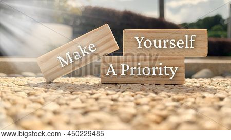 Make Yourself A Priority Text On Wooden Blocks With Bright Sun And Park Background.