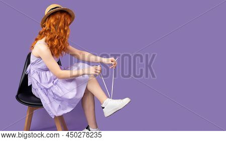 Side View Photo Of A Redhead Young Pretty Woman In Sundress And Strae Hat Holds Shoelaces In Hands O