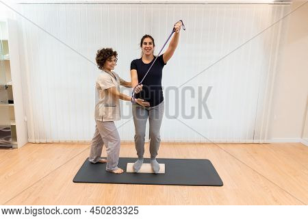 A Pregnant Woman Standing On A Proprioceptive Trunk Or Wooden Roller With An Elastic Band With Physi