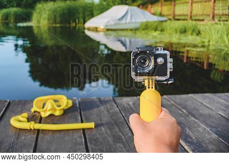 Waterproof Action Camera Close-up With A Yellow Float In A Man's Hand. Background Mask For Snorkelin
