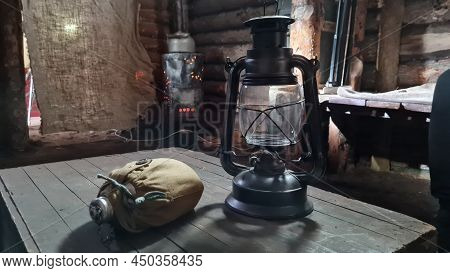 A Wooden Dugout In Which A Kerosene Lamp Burns. Light From The Window Penetrates Into The Room.