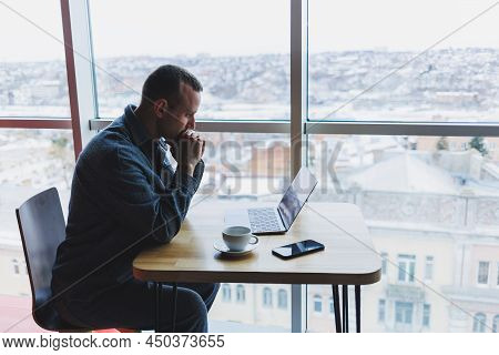 A Young Successful Businessman In A Suit Drinks Coffee And Works In A Cafe On Wireless Free Internet