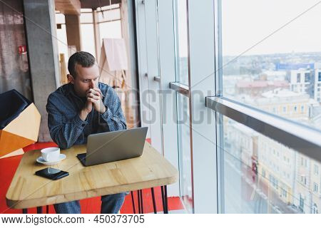 A Young Successful Businessman In A Suit Drinks Coffee And Works In A Cafe On Wireless Free Internet
