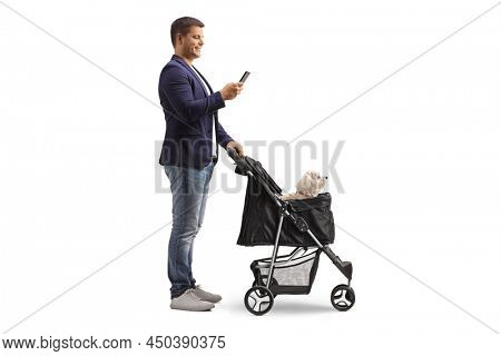 Full length profile shot of a man standing with a dog troller and looking at a smartphone isolated on white background
