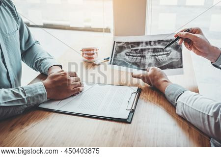 Dentist With Male Patient Presenting Discussing Dental Problems X-ray Image Film In Dental Office