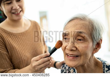 Happy Asian Senior Woman Or Mother Enjoy Makeup On Face, Joyful Female Caregiver Or Daughter Is Help