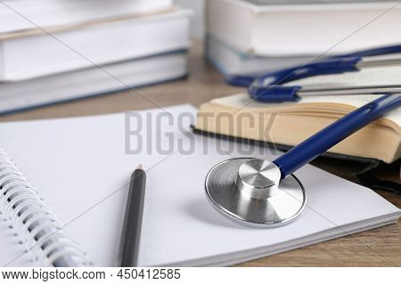 Student Textbook, Blank Notebook, Pencil And Stethoscope On Wooden Table, Closeup. Medical Education