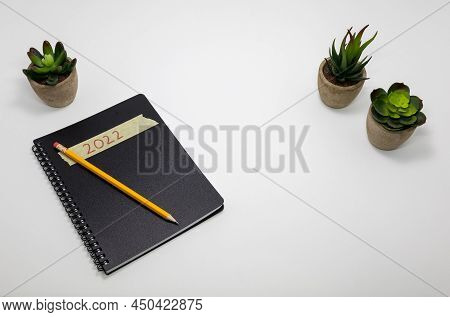 Spiral Notebook On White Desk With Small Plants