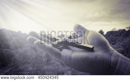 Hand Holding Holy Cross With Bright Shining Light.