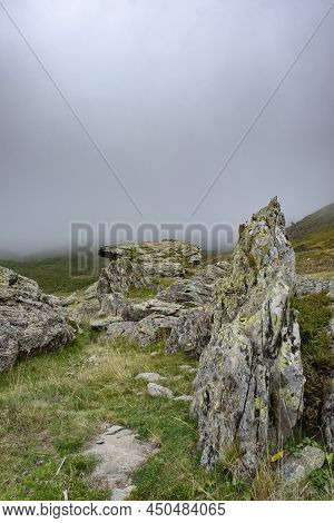 High Mountain Scenery With Granitic Rocks Covering With Lichens In The Foreground And A Thick Fog Ba