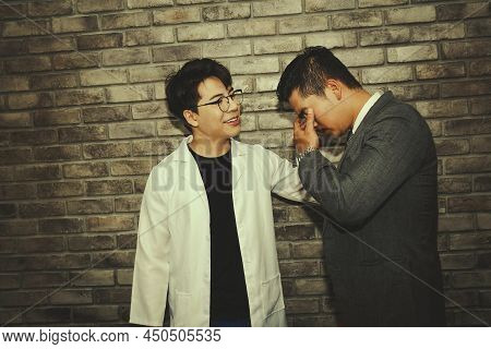 The Business Man Stands Up Sad And Hands Off His Face With A Doctor Standing Nearby. (when A Serious