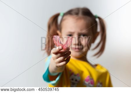 Cute Little Girl With Blond Hair Is Holding A Pink Dental Myofunctional Trainer