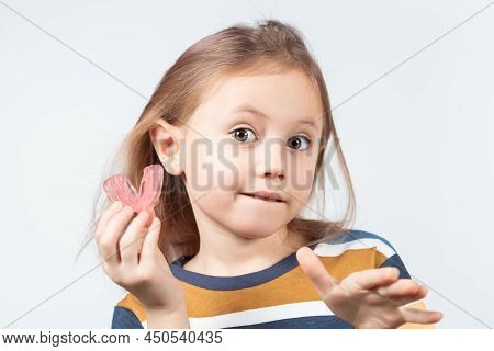 Cute Little Girl With Blond Hair Is Holding A Pink Dental Myofunctional Trainer