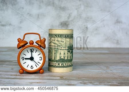 Alarm Clock Set At 9 O'clock With Banknotes On Table. Business And Tax Concept.