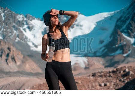 A Young Athletic Girl Drinks Water, Isotonic From A Bottle During Training, Trail Running In The Sno