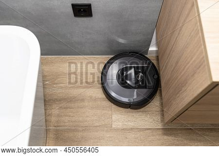 A Modern Robotic Vacuum Cleaner Cleans The Ceramic Tiles In The Bathroom Next To The Wall Mounted Ca