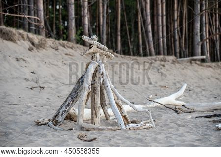 Stacked Light Trees And Branches By The Sea, Like A Wigwam Or A Bonfire. Natural Landscape In Latvia