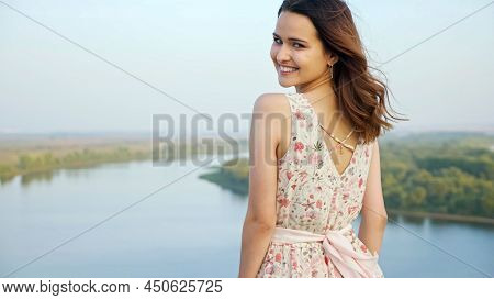Attractive Brunette Woman With Loose Hair In Dress With Flower Pattern Hugs Shoulders On Riverbank O