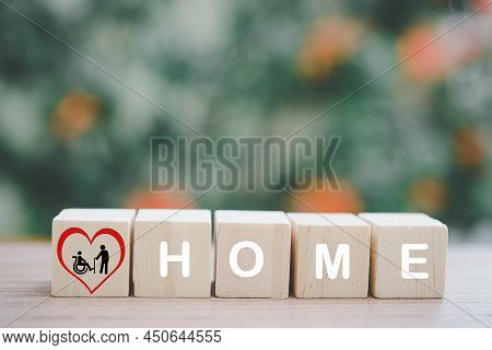 Elderly And Disability Person In Red Heart Shape  Icon On Wood Cube Block And Home Word On Blurred N