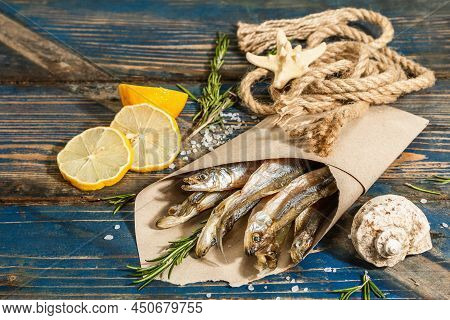 Sun-dried Smelt In A Paper Package. Salted Fish With Marine Decor. Lemon, Fresh Rosemary, Sea Rope